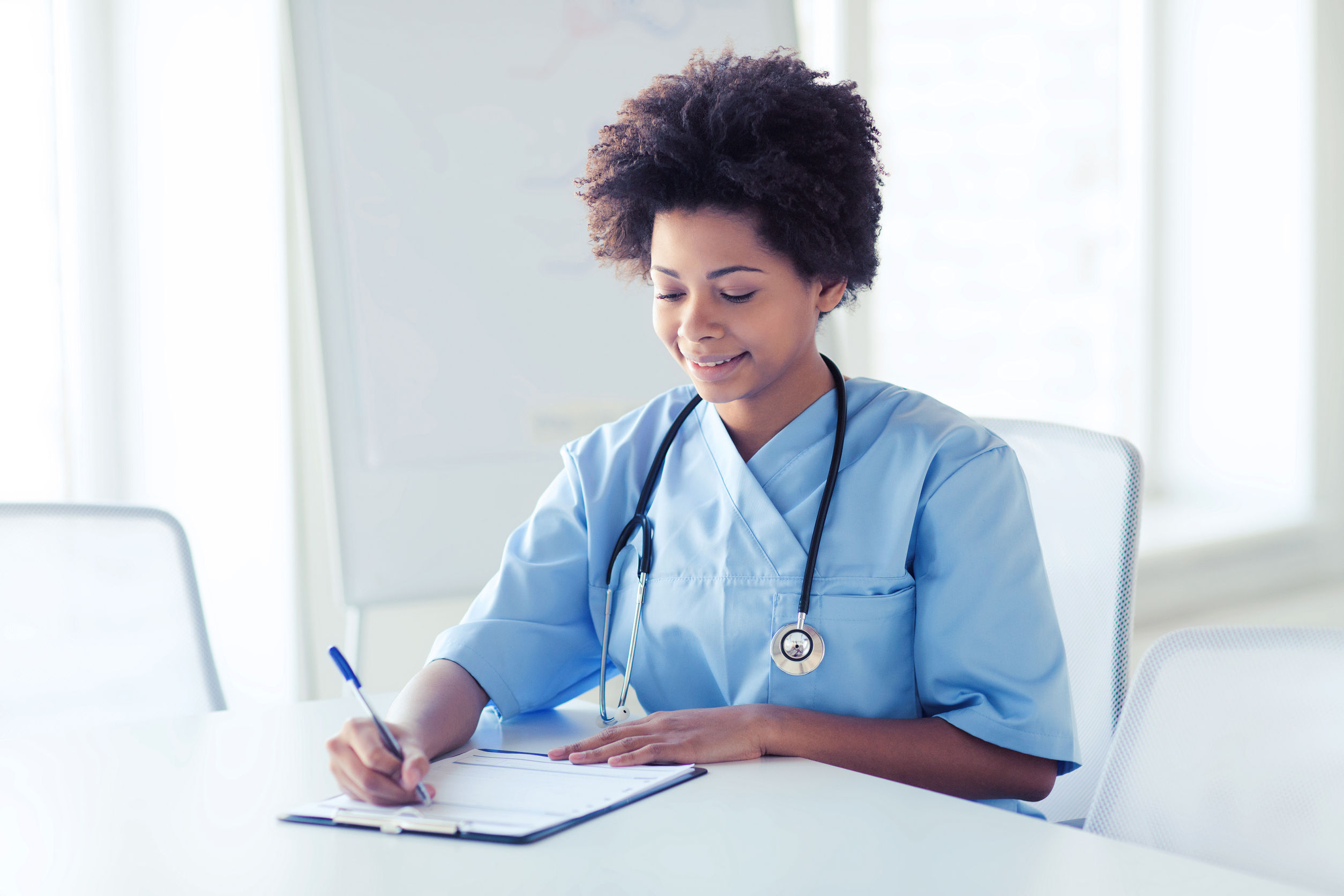 69836525 – happy female doctor or nurse writing to clipboard